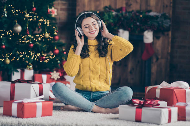 pełna długość ciała rozmiar zdjęcia radujących się miły uradowany dziewczyna słuchając muzyki świątecznej radując się z nowego roku atmosfera sobie żółty sweter dżinsy dżinsy siedzi na podłodze - image date audio zdjęcia i obrazy z banku zdjęć
