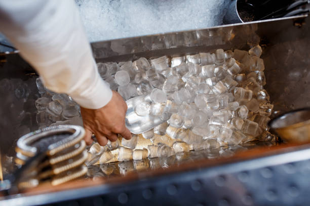 barman scoops up ice for making alcohol cocktail