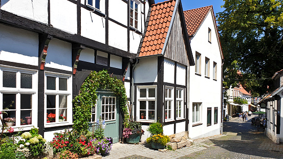 Tecklenburg, Germany - 27 July, 2019: Street view of idyllic and medieval Tecklenburg in Münsterland, a warm sunny day, with tourists and flowering potted plants in front of the black and white half-timbered houses.