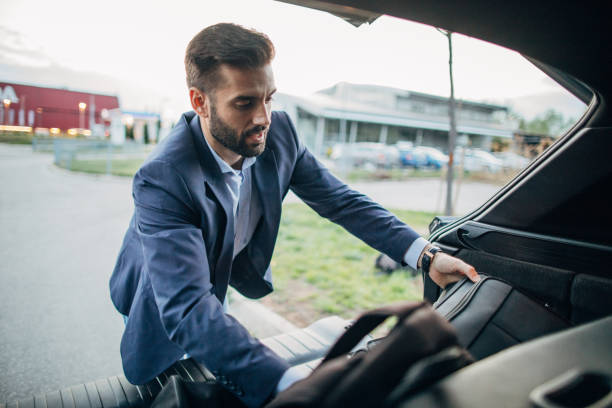 Businessman putting luggage in the car trunk and preparing for the road trip