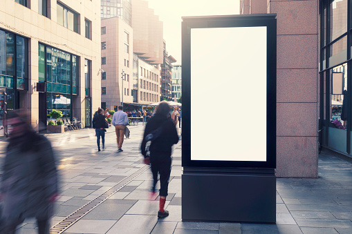 An modern electronic billboard in a city street with people on the move.
