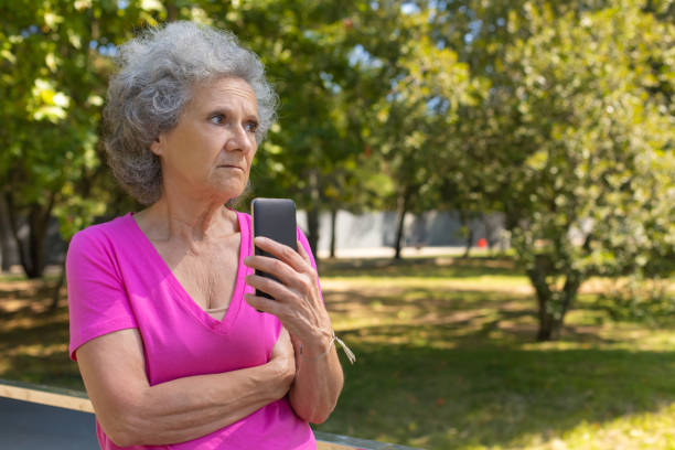 istock Upset old lady holding smartphone and looking away 1170694820