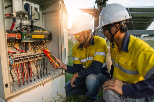 Photo of Workers use clamp meter to measure the current of electrical wires produced from solar energy for confirm to normal current