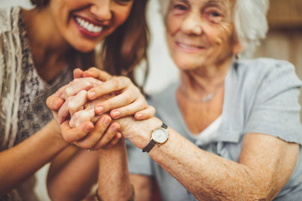 primo primo di un'infermiera sorridente che tiene la mano di una donna anziana - holding hands human hand senior adult consoling foto e immagini stock