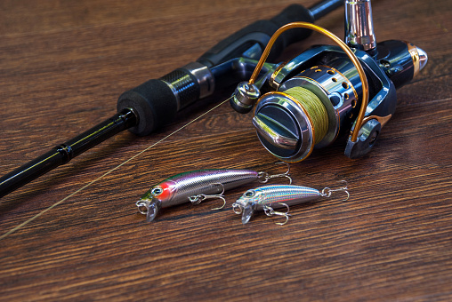 Fishing tackle - fishing spinning, hooks and lures on darken wooden background.