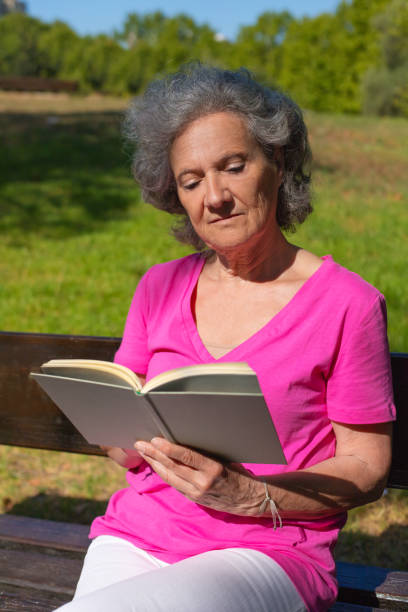 istock Peaceful calm old lady enjoying book story in park 1170699757