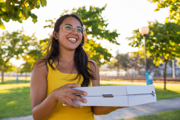 felice gioiosa donna latina che porta la pizza per la festa all'aperto - two party system foto e immagini stock