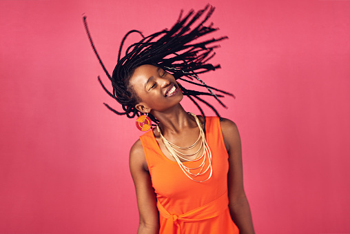 Studio shot of an attractive young woman posing against a pink background