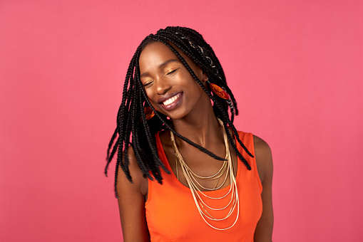 Studio shot of an attractive young woman posing against a pink background