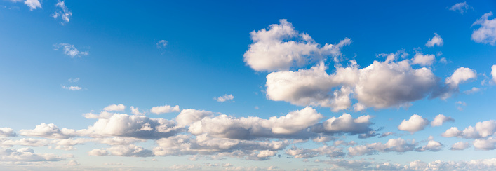 A high resolution panoramic image of an expanse of cumulus clouds and blue sky.