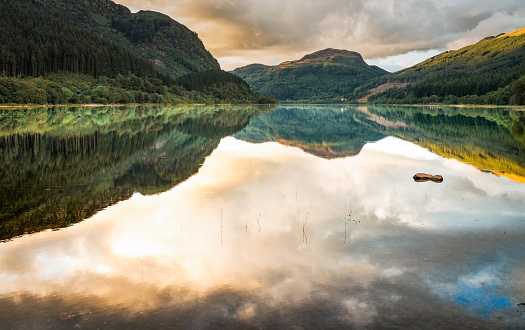 Calm water reflecting the mountains and cloudscape above Loch Lubnaig in Scotland.