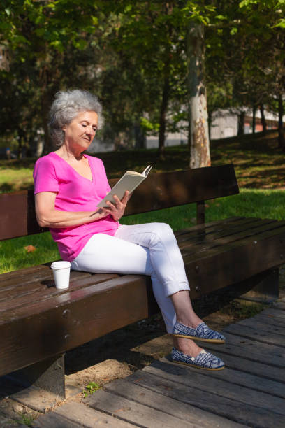 istock Peaceful inspired old lady enjoying novel in park 1170704085