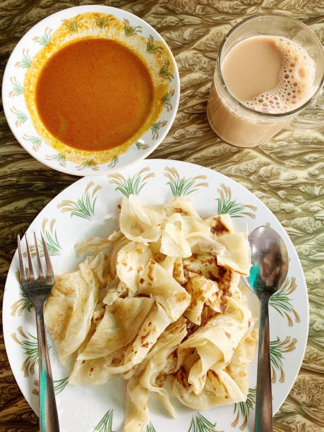 Roti Canai with curry and Teh Tarik (pulled milk tea), a traditional Malaysian breakfast at a Mamak store Roti Canai, curry and milk tea at a Mamak stall roti canai stock pictures, royalty-free photos & images