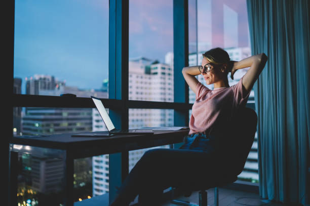 istock Attractive female freelancer resting after complete work in office on laptop with blank screen. Student enjoying recreation time watching movie on computer at home interior with evening city view 1170706678