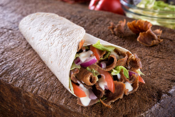 Doner Donair Kebab Wrap A delicious doner donair kebab wrap with spicy meat, lettuce, tomato, red onion and sauce. wrap sandwich photos stock pictures, royalty-free photos & images