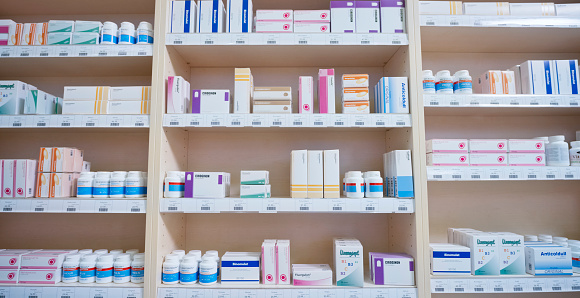 Shelves stacked with medicine bottles and boxes in pharmacy.