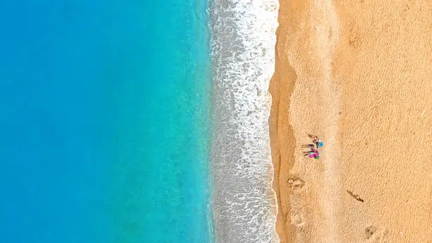 Photo of Beach aerial. People relaxing on a tropical beach near the water. Top view.