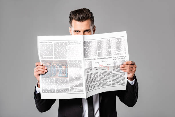 istock businessman in black suit with newspaper isolated on grey 1170710683