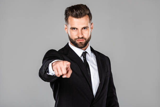 istock successful businessman in black suit pointing with finger at camera isolated on grey 1170710707
