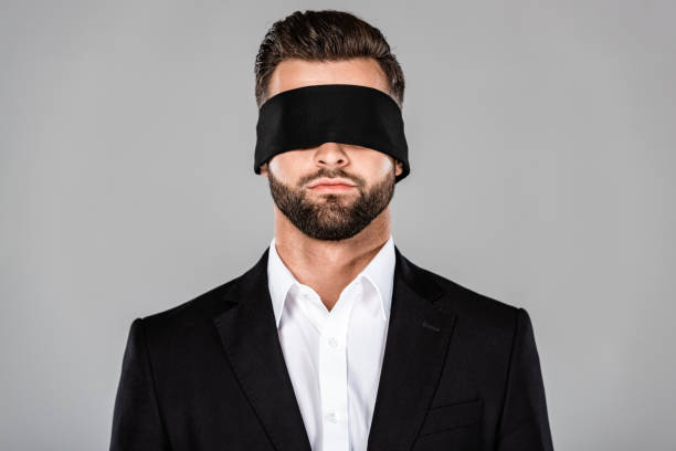 barbudo guapo hombre de negocios con los ojos vendados en traje negro aislado en gris - venda de ojos fotografías e imágenes de stock