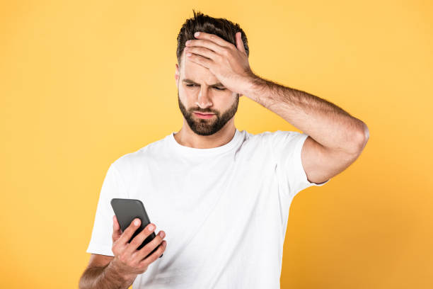 istock upset man in white t-shirt with facepalm using smartphone isolated on yellow 1170710742