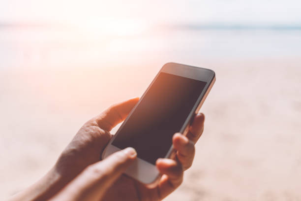 istock Close up woman hand using smart phone on tropical sunset beach abstract background. 1170713878