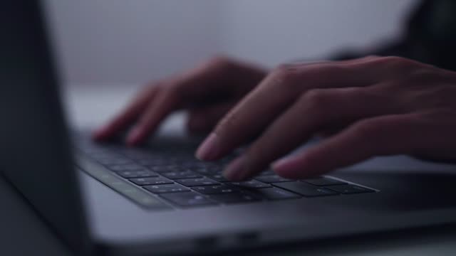 Hands of woman typing on a laptop computer. She hastened race against time to get work done on the night.