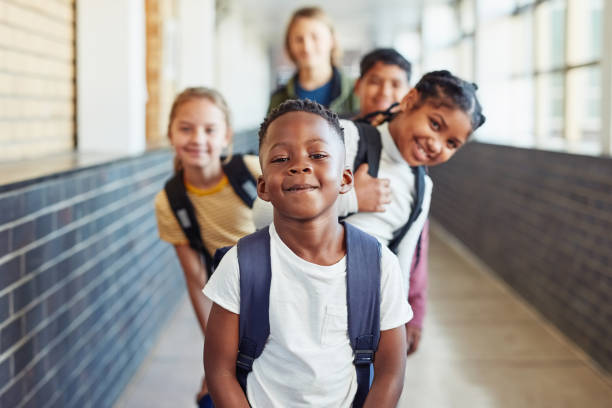 Let's learn something new today Portrait of a group of young children standing in a line in the hallway of a school primary age child stock pictures, royalty-free photos & images