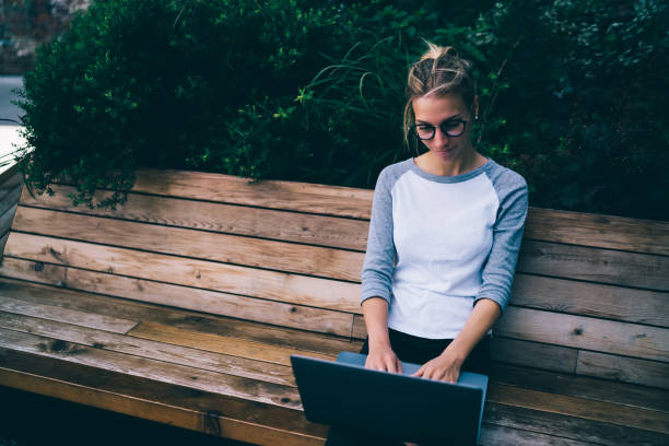 istock Hipster girl typing feedback on laptop computer using  4G connection and laptop computer resting on bench,young female student chatting with friends in social networks spending free time in town 1170720215