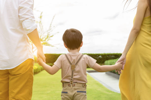 ragazzo carino o bel figlio che cammina con i genitori. padre e madre che si tengono per mano bambino con amore e felicità al mattino con aria fresca. sono una famiglia felice. papà mamma figlio trascorrere del tempo insieme - couple human hand holding walking foto e immagini stock