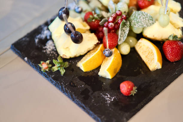 istock Fruit sliced on a stylish plate. Pineapple, pear, orange, apple, grape, wild strawberry. 1170721909