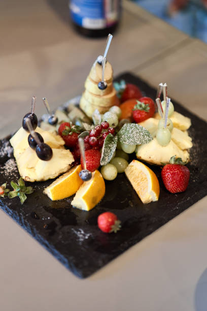 istock Fruit sliced on a stylish plate. Pineapple, pear, orange, apple, grape, wild strawberry. 1170721953