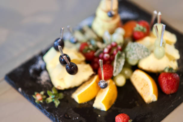 istock Fruit sliced on a stylish plate. Pineapple, pear, orange, apple, grape, wild strawberry. 1170722080