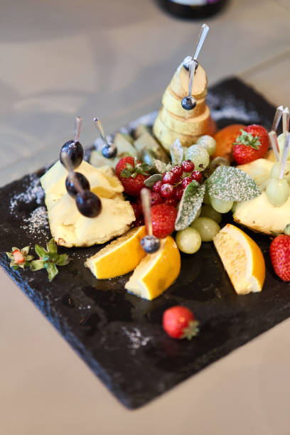 istock Fruit sliced on a stylish plate. Pineapple, pear, orange, apple, grape, wild strawberry. 1170722124