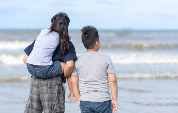 istock father and two kids walking on beach, 1170722263