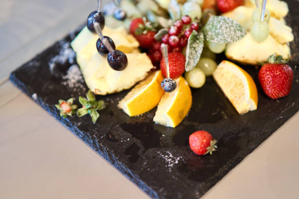 istock Fruit sliced on a stylish plate. Pineapple, pear, orange, apple, grape, wild strawberry. 1170722349