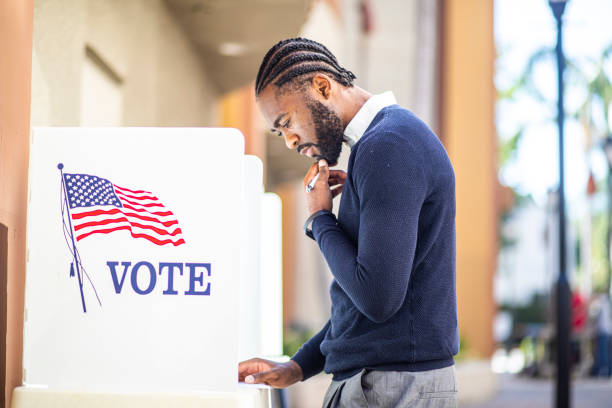 Millenial Black Man Voting in Election A millennial black man voting at a voting booth in an election. democratic party usa photos stock pictures, royalty-free photos & images
