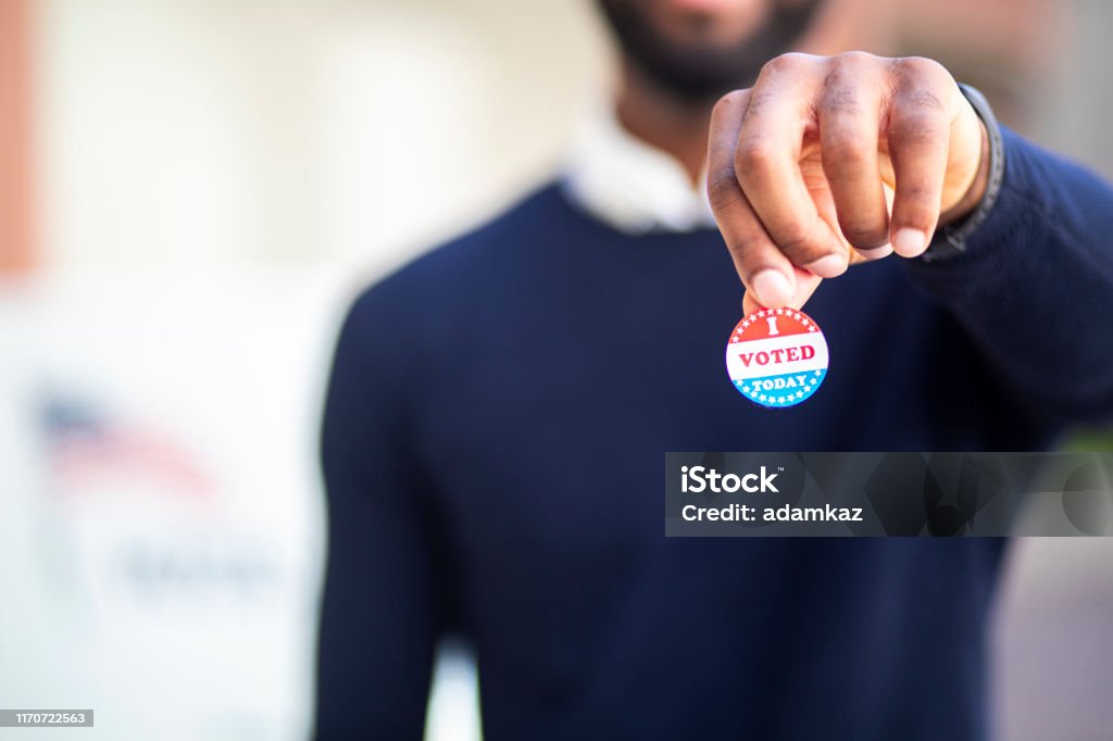 Young Black Man with I voted Sticker A young black man with his I voted sticker after voting in an election. Voting Stock Photo