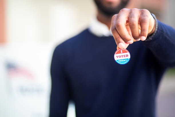 Young Black Man with I voted Sticker A young black man with his I voted sticker after voting in an election. voting stock pictures, royalty-free photos & images