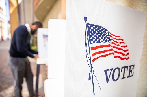 A millennial black man voting at a voting booth in an election.