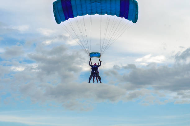 Paraglider tandem fly against the blue sky, paragliding guided by a pilot.