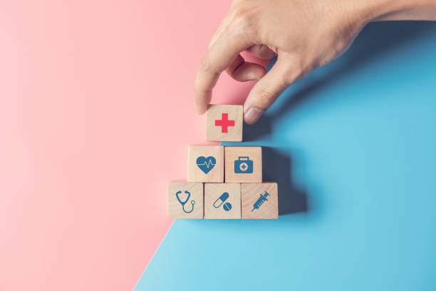Health Insurance Concept, Hand of man arranging wood cube stacking with icon healthcare medical on pastel blue and pink background. Health Insurance Concept, Hand of man arranging wood cube stacking with icon healthcare medical on pastel blue and pink background, copy space. patient blood management stock pictures, royalty-free photos & images