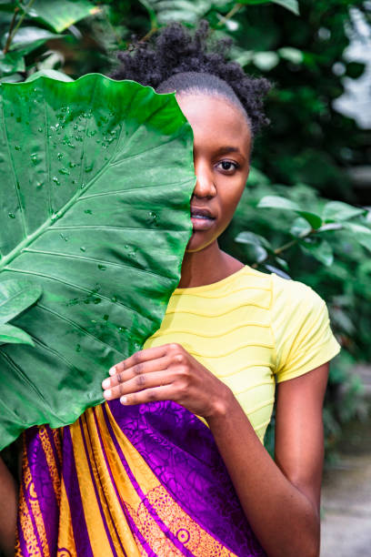 istock African girl holds palm leaf and covers her face 1170727218