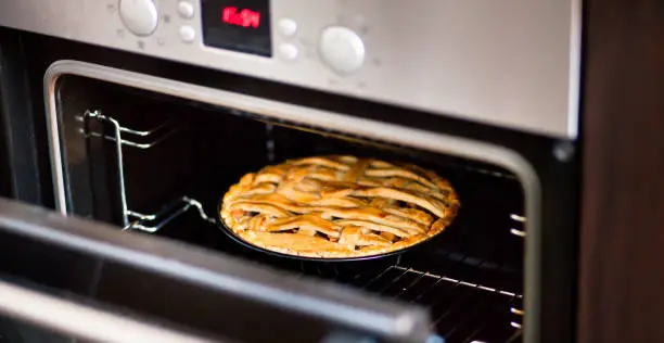 baking traditional apple pie in the oven in the kitchen.
