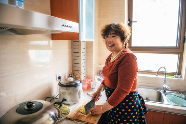 smiling chinese grandmother cooking in kitchen