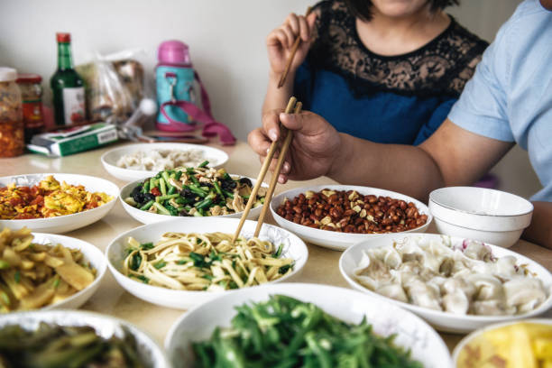 man eating chinese noodles with chopsticks at lunch table