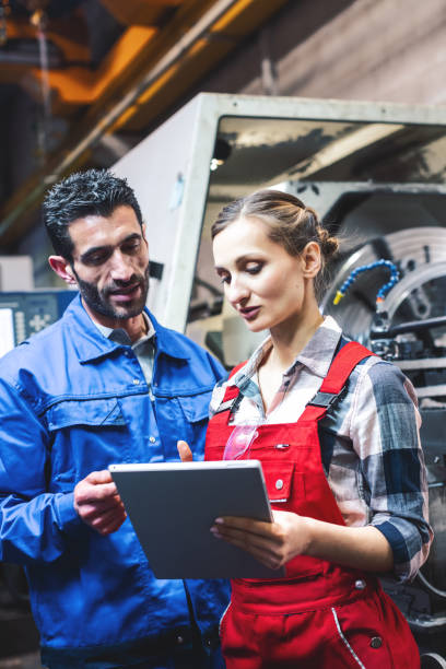 istock Woman and man manufacturing worker in discussion 1170733449
