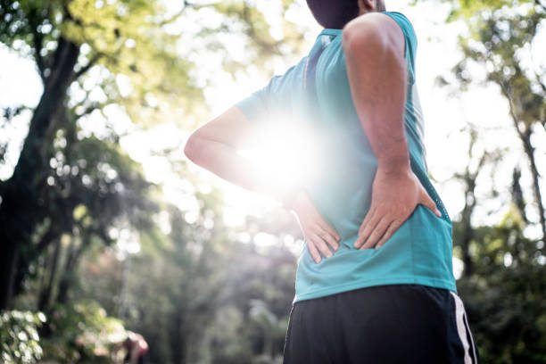 Sportsman feeling backache at a park Sportsman feeling backache at a park lower back pain stock pictures, royalty-free photos & images