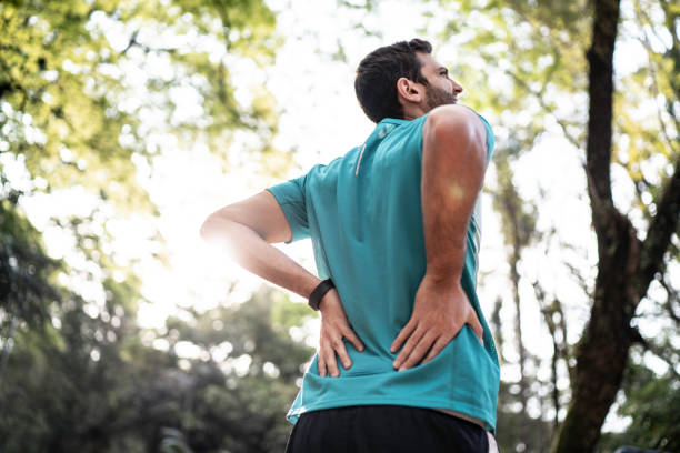 sportivo che si sente mal di schiena in un parco - backache foto e immagini stock