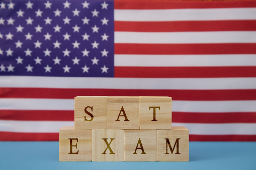 SAT Exam in WOoden blook letters on US flag.